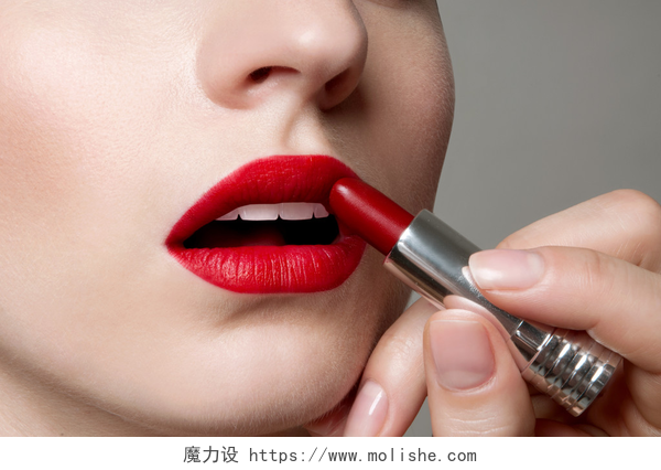 白色背景上用手在嘴唇画口红仕女画在完美的嘴唇上应用红色唇膏弥补. 